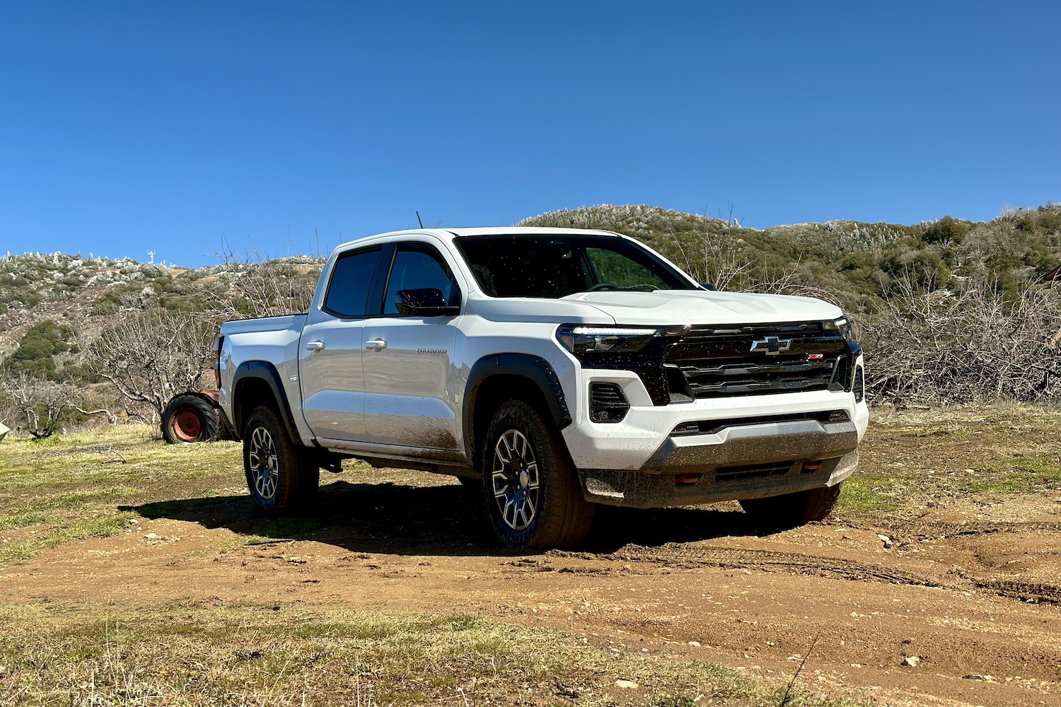 Front end angle of the 2023 Chevrolet Colorado Z71 from driver's side parked in a muddy field.