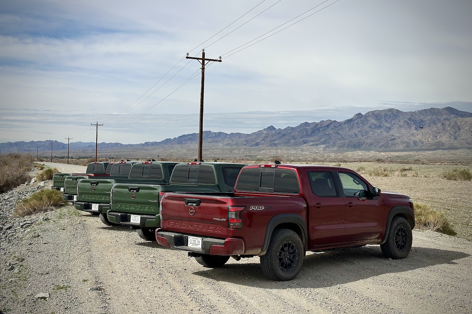 Rear end angle of the 2022 Nissan Frontier Pro-4X parked on a dirt trail in front of mountains.