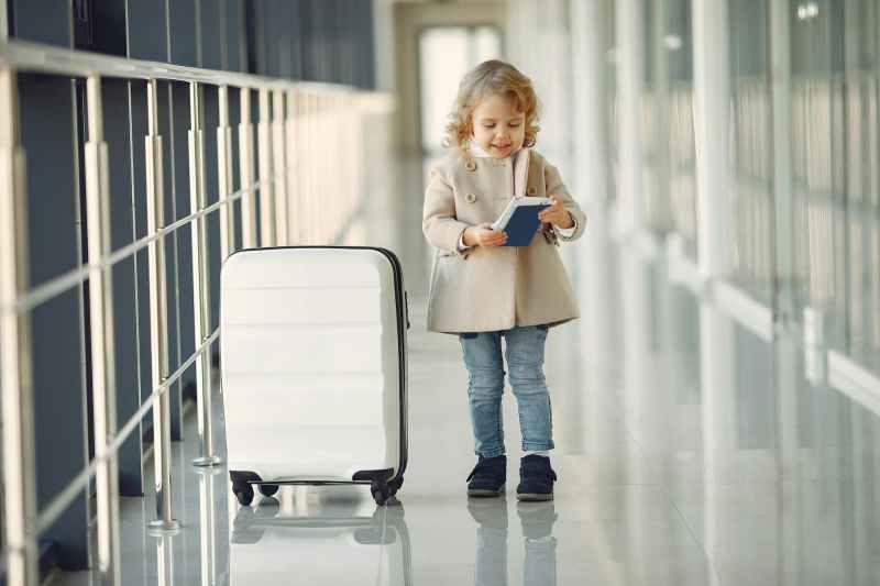 little girl standing next to suitcase in airport